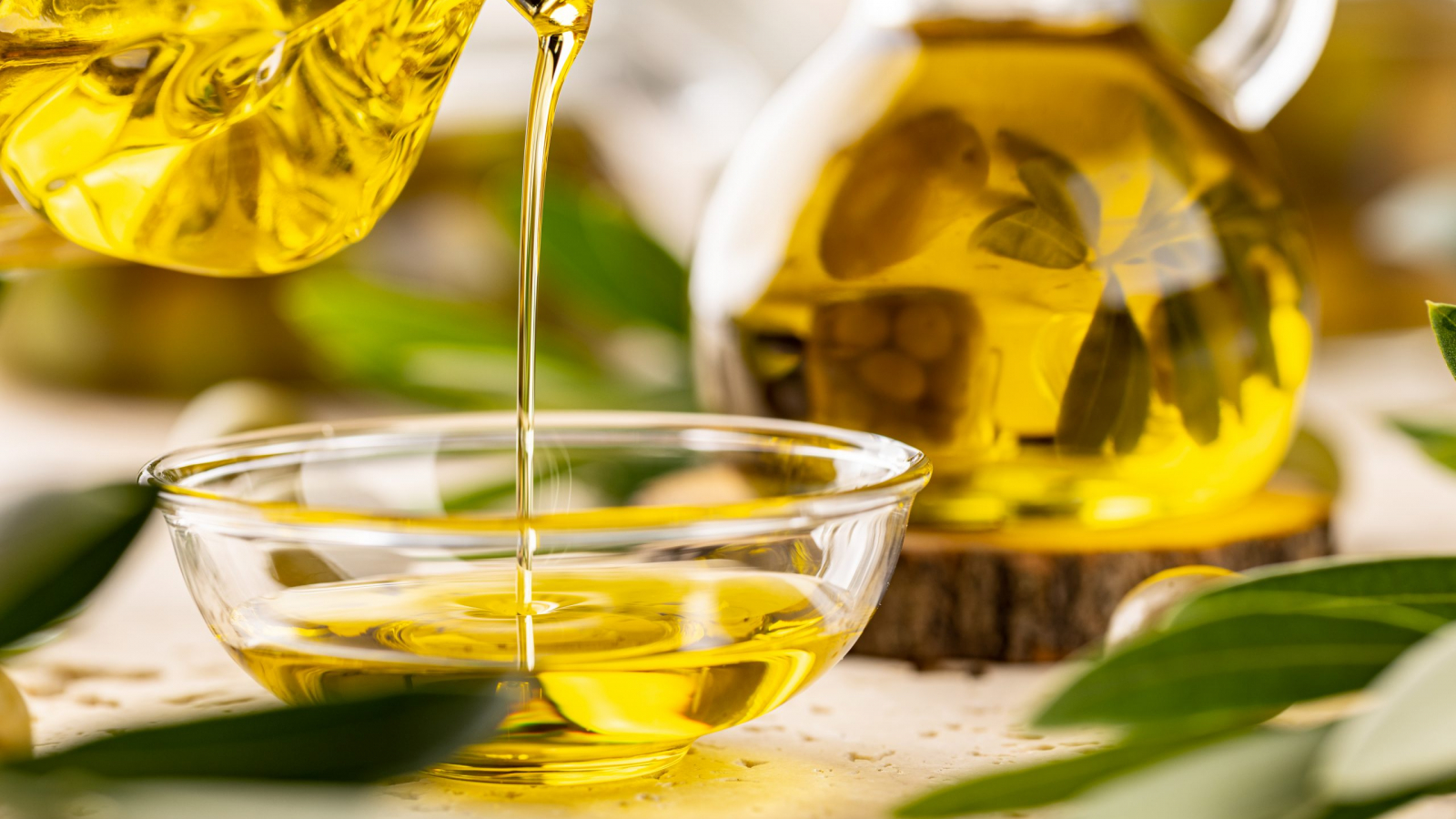 Bottle pouring virgin olive oil in a bowl close up