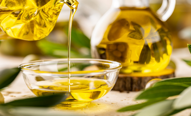 Bottle pouring virgin olive oil in a bowl close up